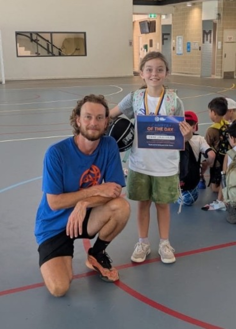 Coach James working with a young player on the basketball court