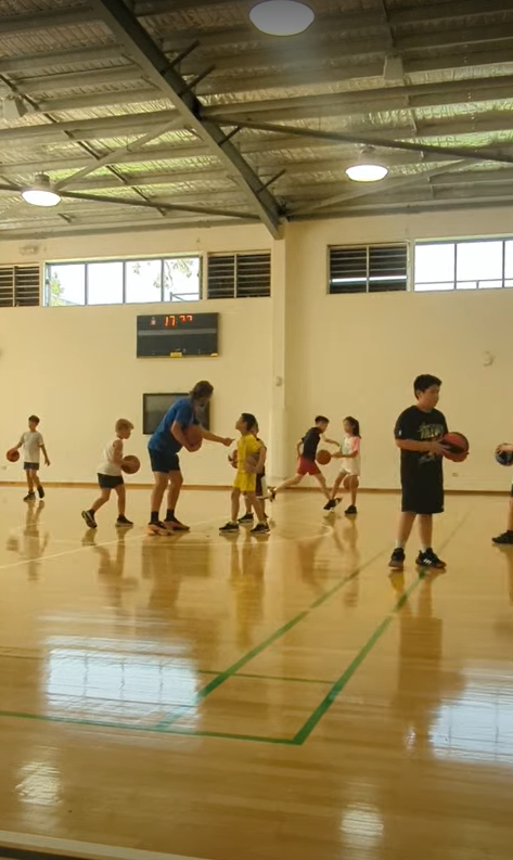 Coach James running a holiday camp basketball session with kids